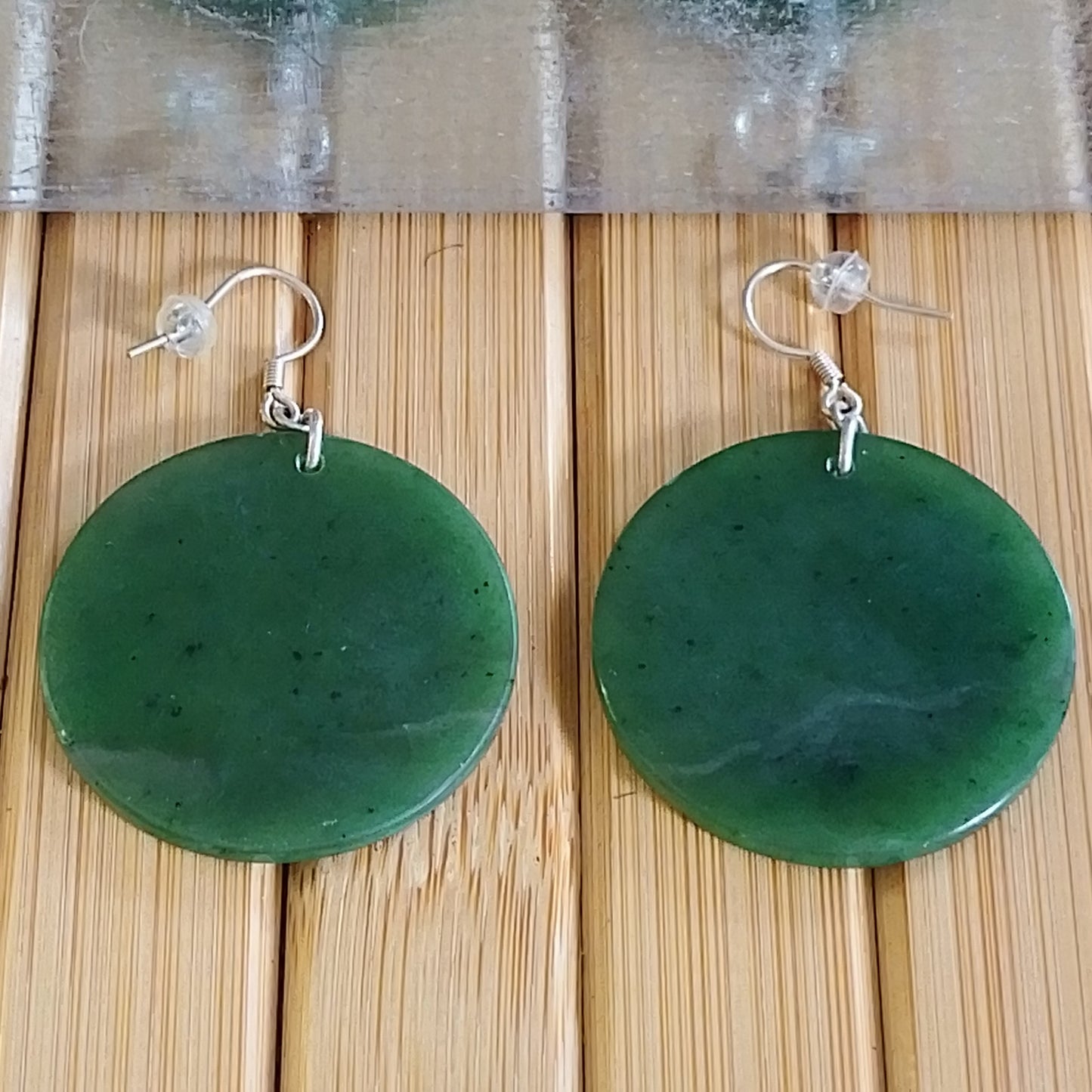 Green jade disc earrings with sterling silver hooks, polished and vibrant, measuring 42mm x 35mm.