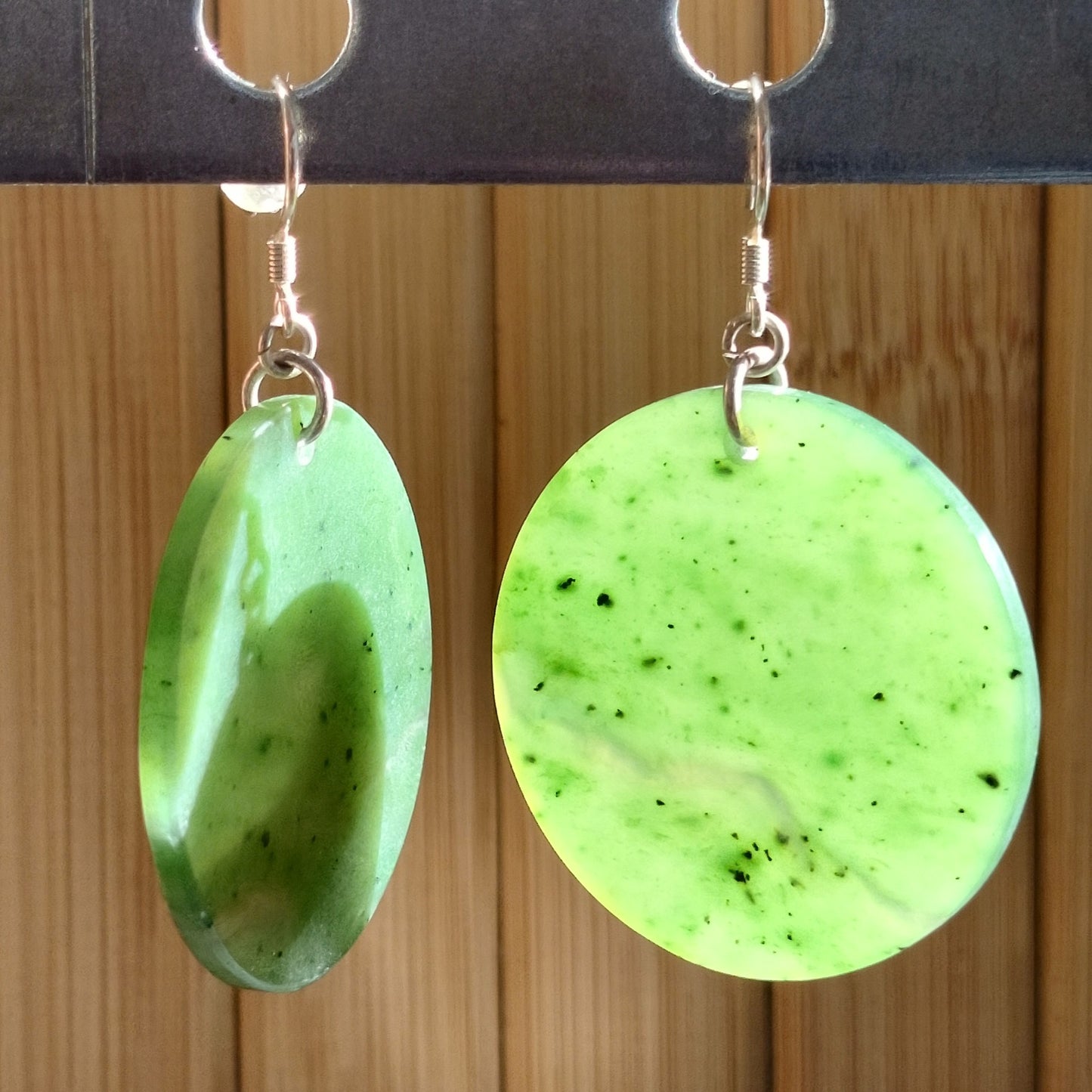 Stunning green jade disc earrings with sterling silver hooks, showcasing vibrant hues and polished discs.