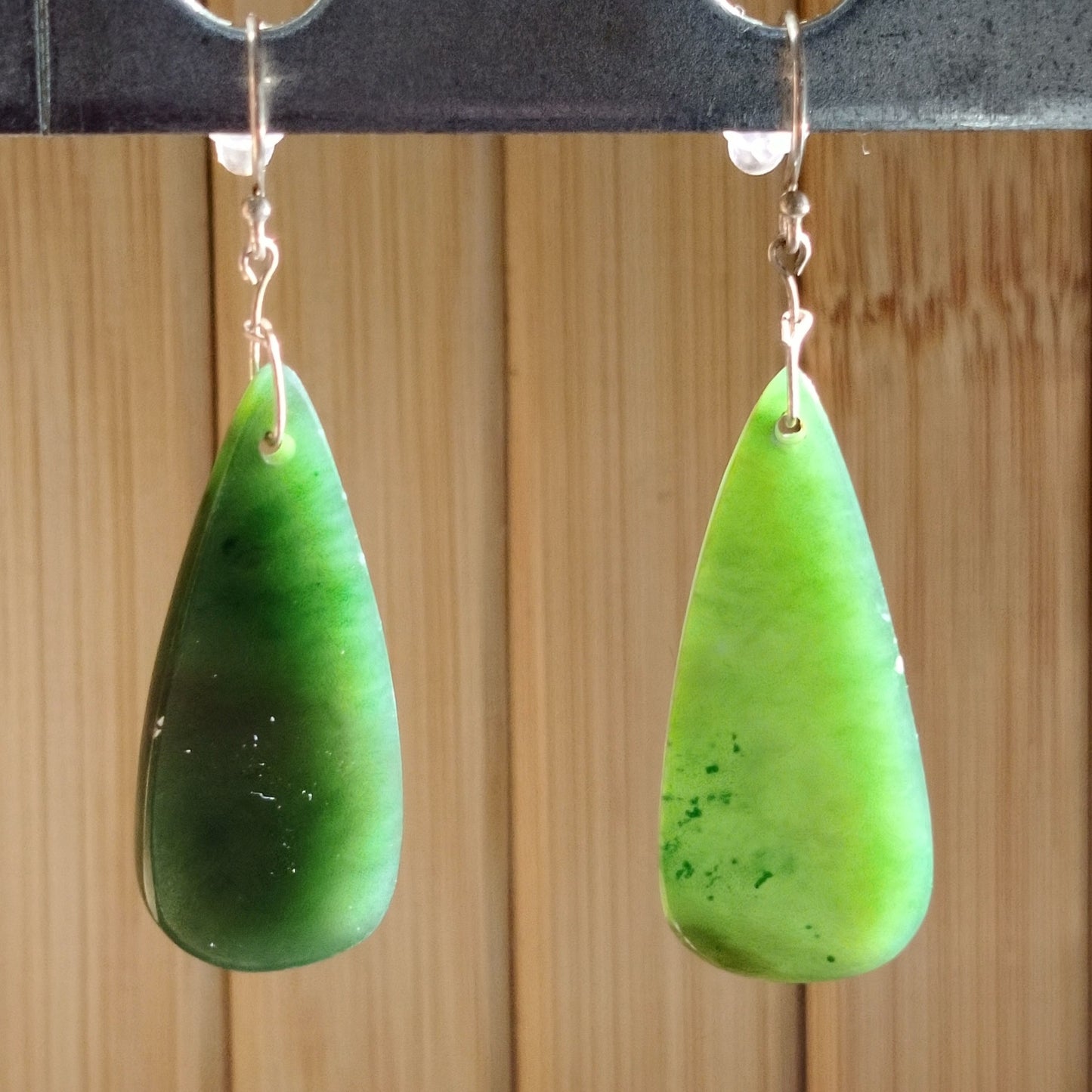 Elegant green jade teardrop earrings with sterling silver hooks, showcasing natural hues and smooth texture.