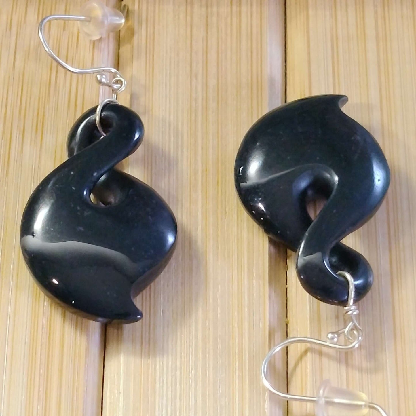 Black jade and sterling silver twist drop earrings showcasing elegant swirl design on a wooden background.
