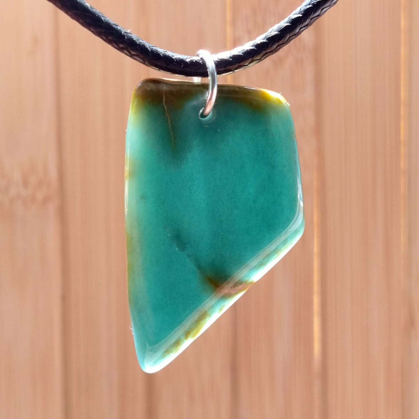 Blue Jade Live Edge Pendant on a black cord, showcasing unique natural artistry and vibrant colors.