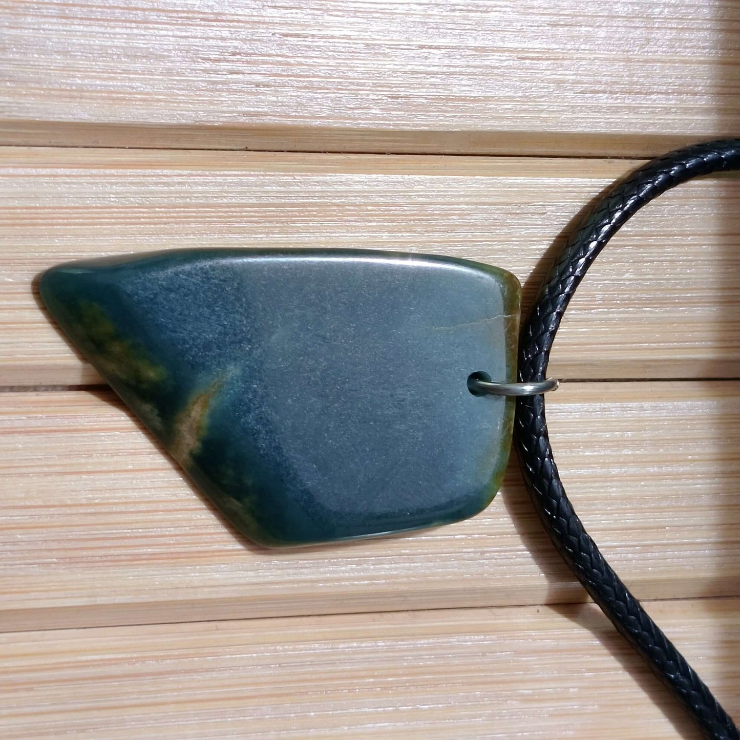 Blue Jade Live Edge Pendant on a cord, showcasing its unique organic shape and natural beauty.