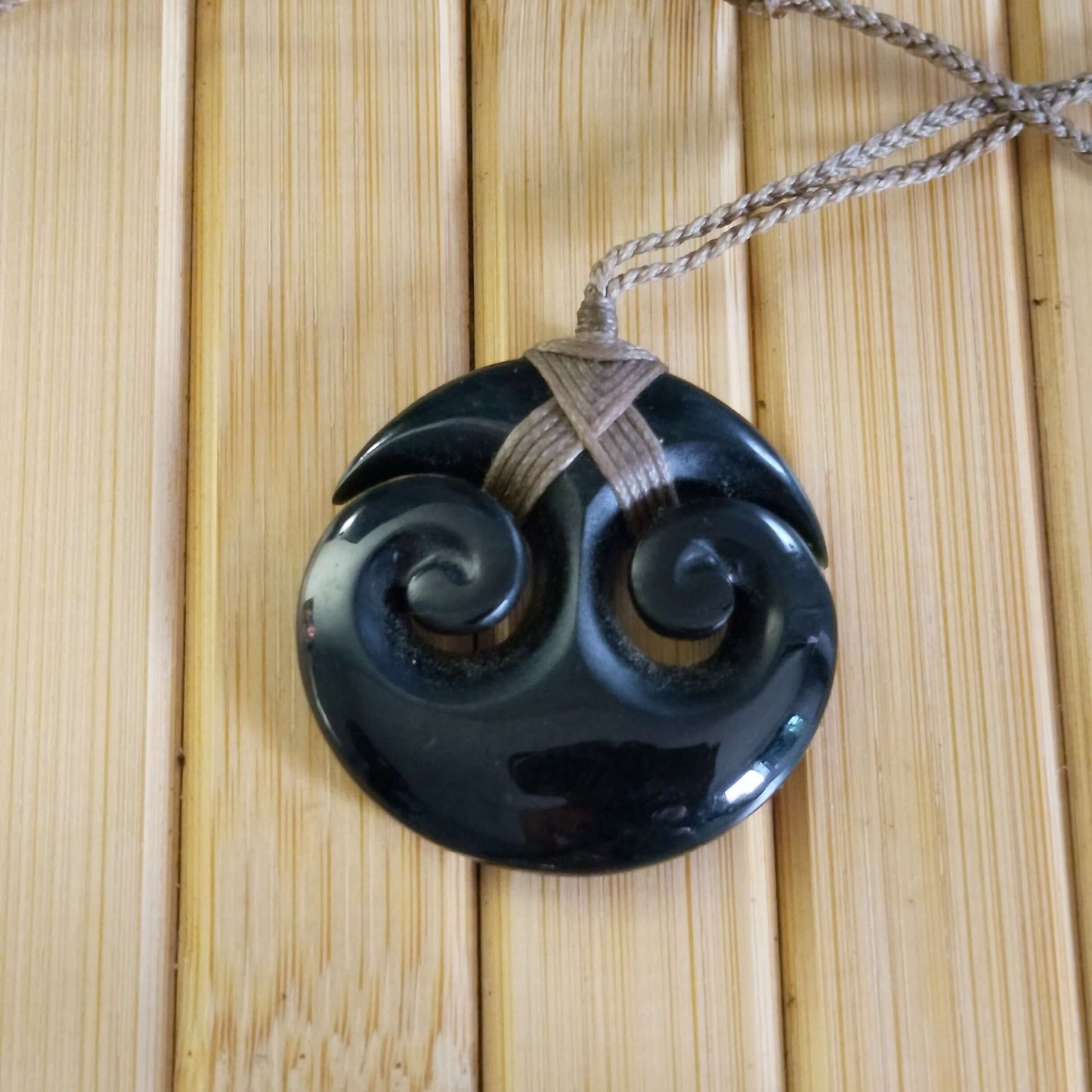 Black Jade Round Double Twirl Pendant on adjustable braided cord, showcasing elegant modern design and deep luxurious tones.