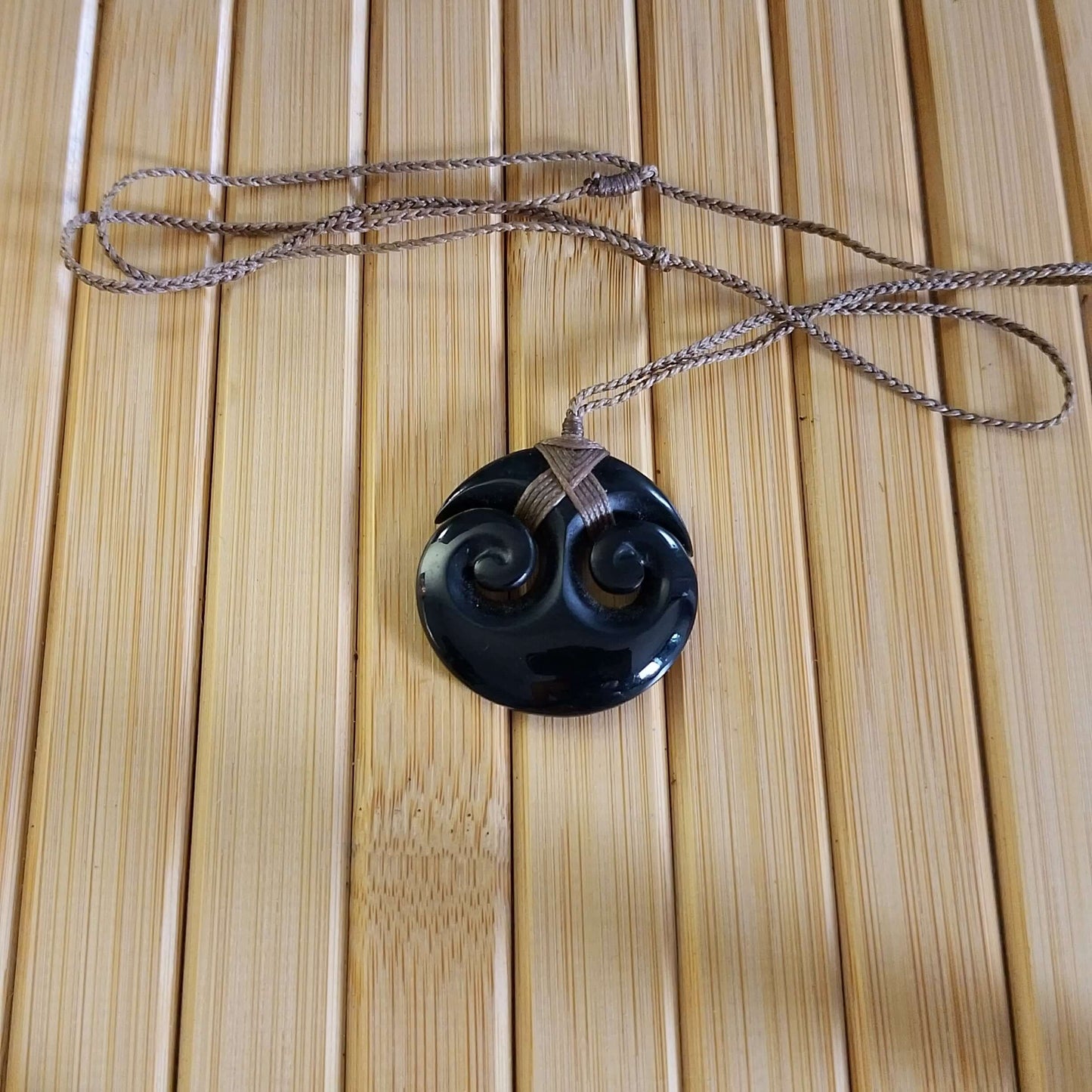 Black Jade Round Double Twirl Pendant on adjustable braided cord, showcasing elegant design and natural beauty.