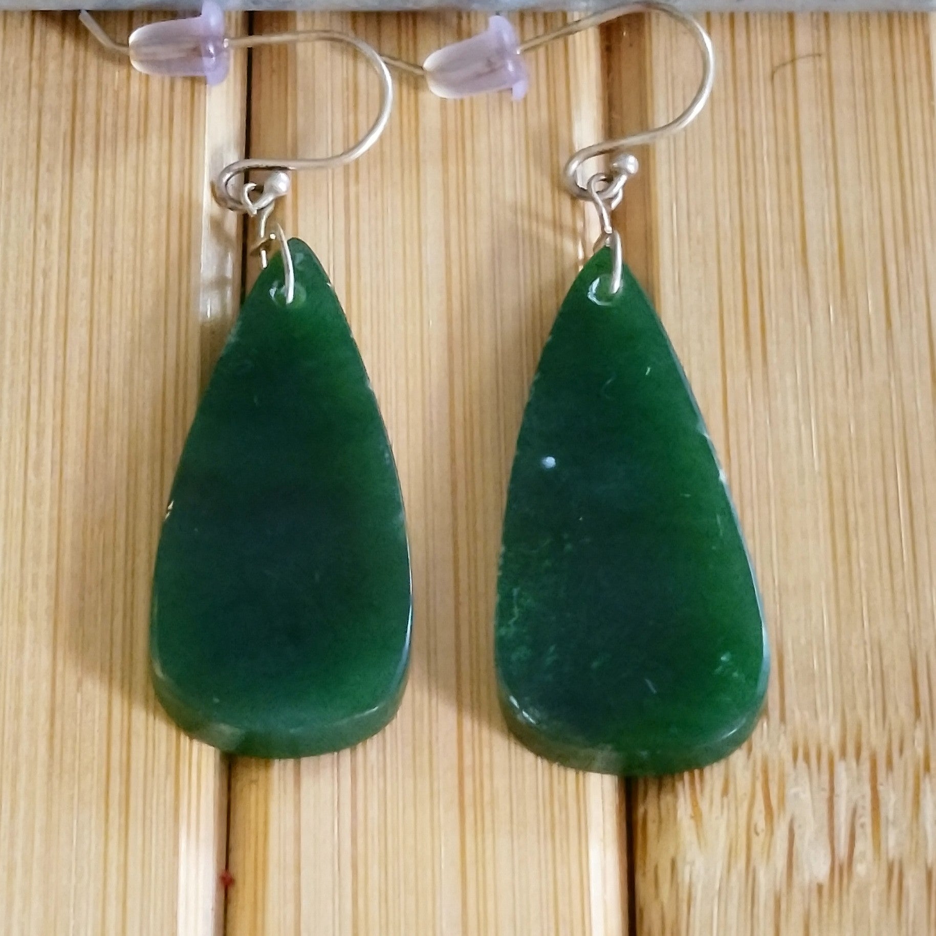Green jade teardrop earrings with sterling silver hooks, showcasing their rich hues and elegant design.