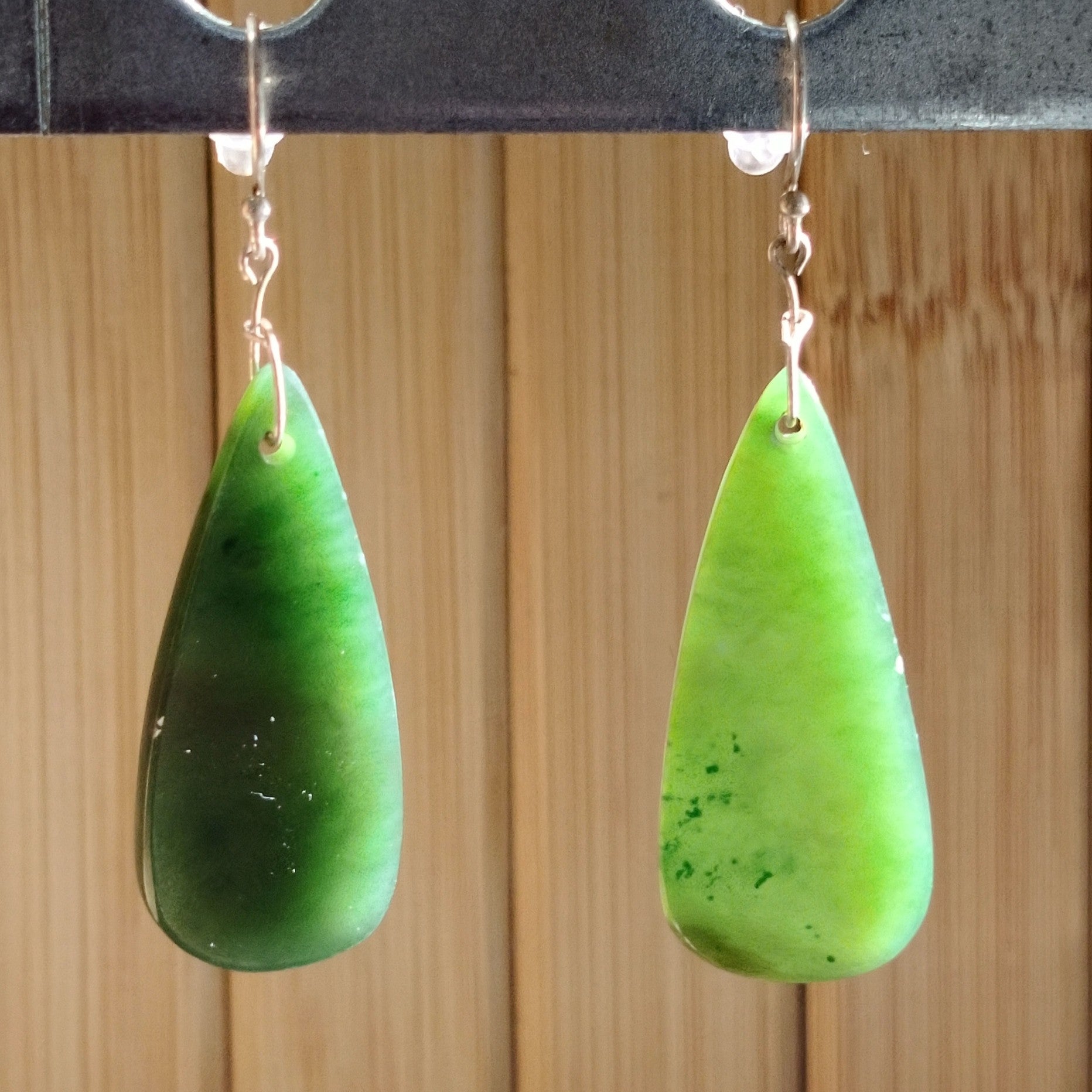Elegant green jade teardrop earrings with sterling silver hooks, showcasing natural hues and smooth texture.
